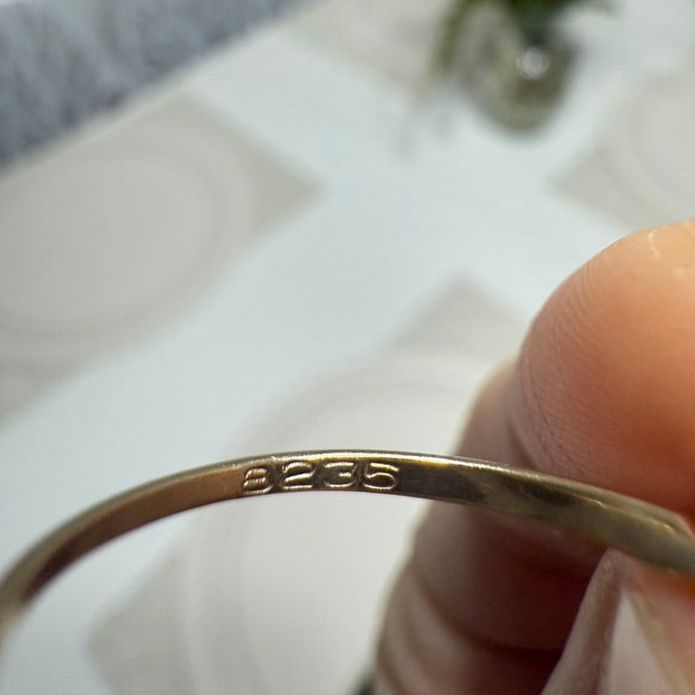 Close-up of 8235 hallmark inside vintage 10K gold ring band, held by hand against a blurred background