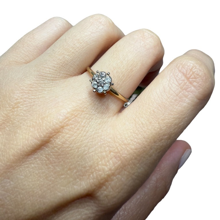 1950s vintage 10K two-tone gold engagement ring with seven diamond floral cluster, shown on hand for scale against white background