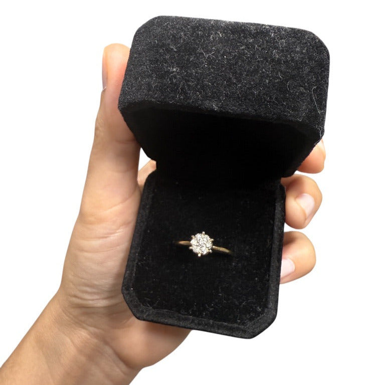 Vintage 10K gold diamond cluster engagement ring in black velvet ring box, held in hand on a white background