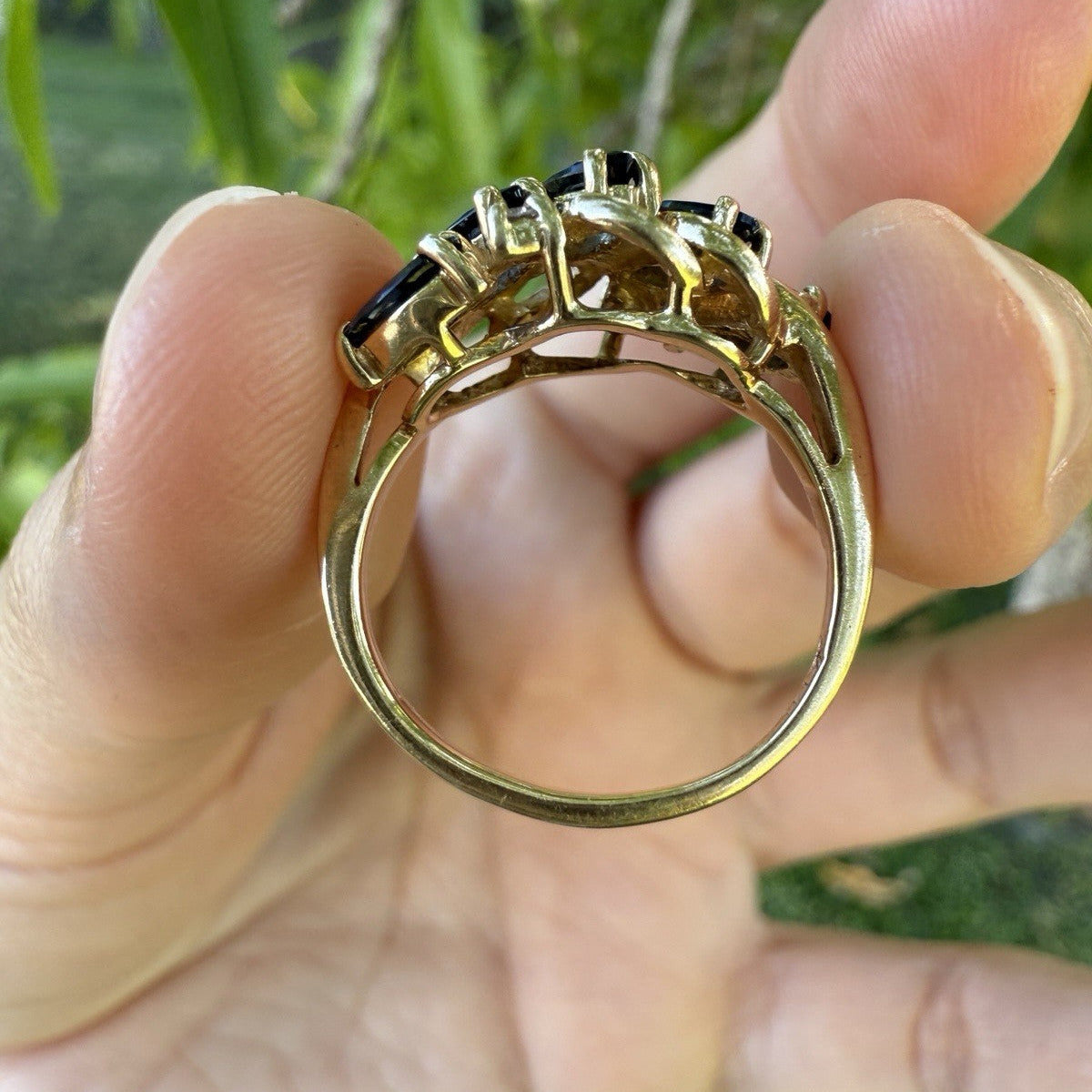 Side profile of vintage 14K gold sapphire and diamond swirl bypass ring showing prong setting and openwork gallery.