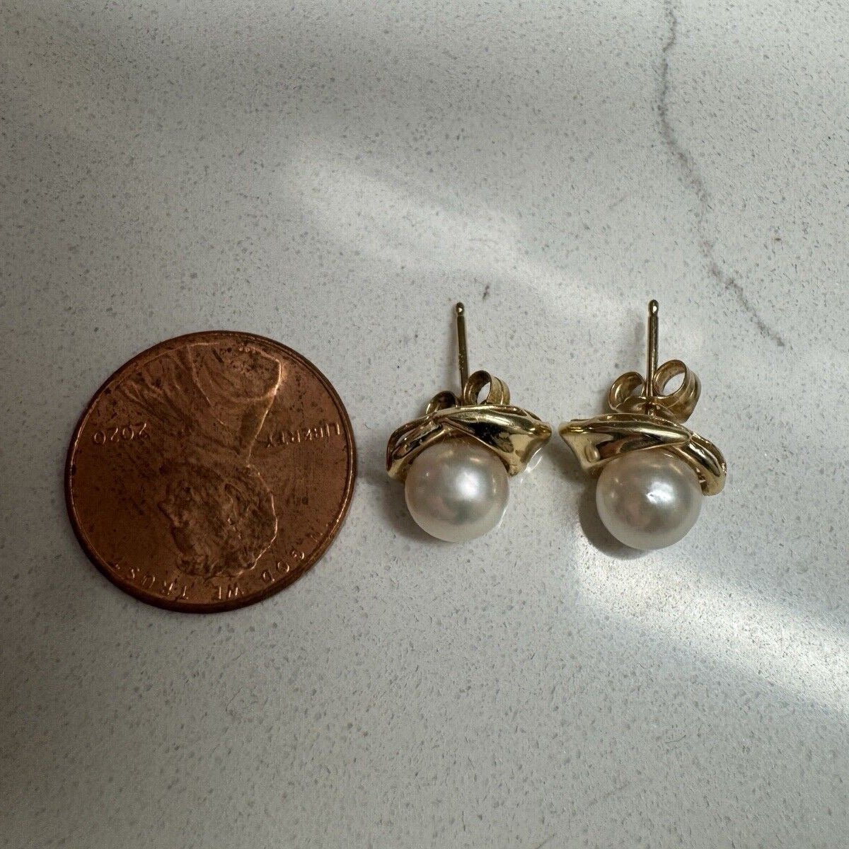 Vintage 14K yellow gold pearl stud earrings shown next to a U.S. penny for size comparison