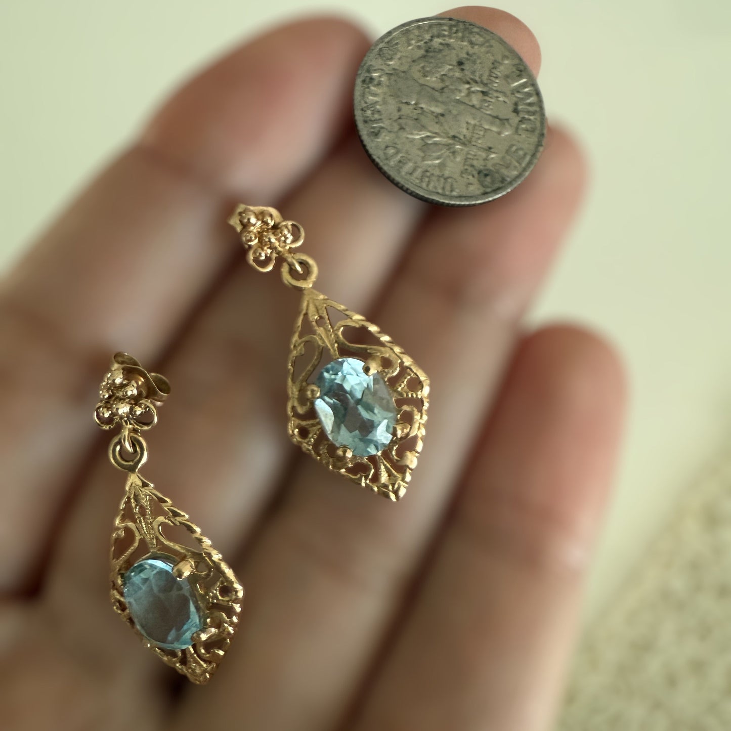 Vintage 14K gold filigree aquamarine drop earrings shown on hand next to a coin for scale