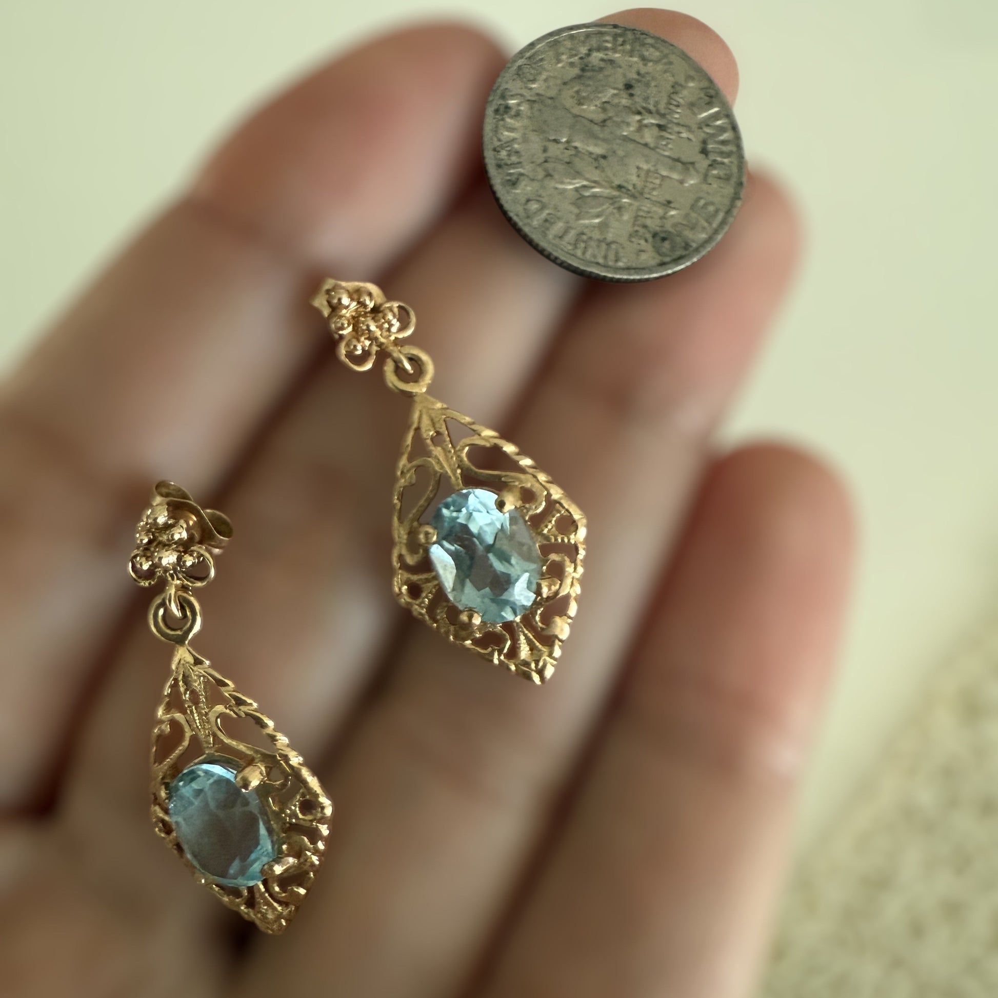 Vintage 14K gold filigree aquamarine drop earrings shown on hand next to a coin for scale