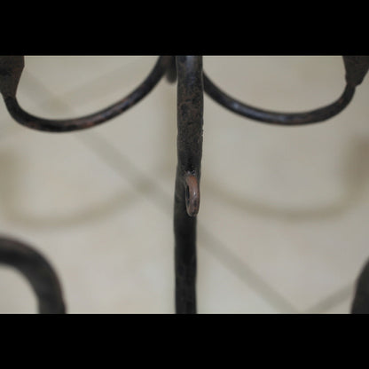 Close-up detail of the wrought iron candelabra stem and curved arms with aged patina.