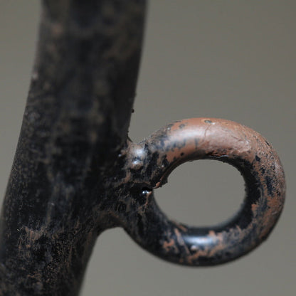 Close-up of a hand-forged iron candle cup showing aged patina and textured surface.