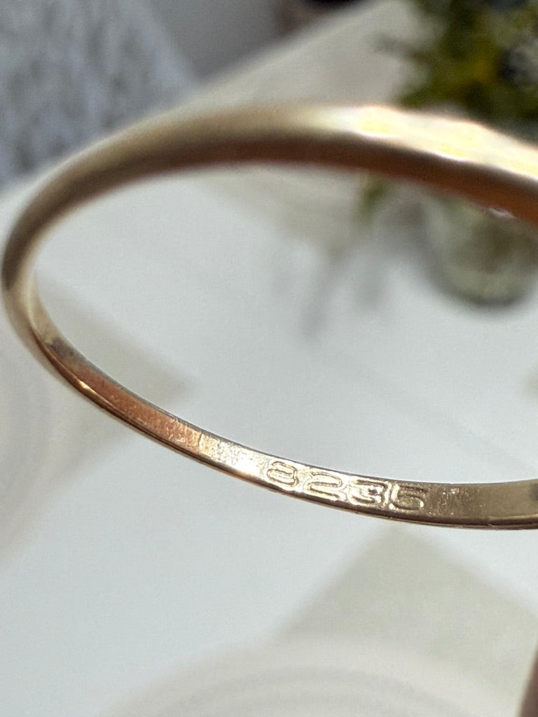 Close-up of 8235 hallmark stamped inside vintage 10K gold ring band, photographed on a white surface