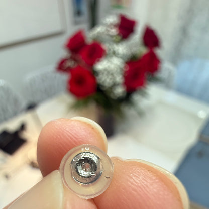 Close-up of sterling silver earring back with clear silicone disc held between fingers