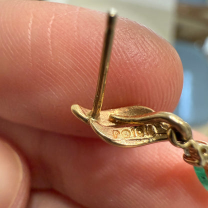 Close-up of 10K gold hallmark on vintage emerald dangle earring post held between fingers
