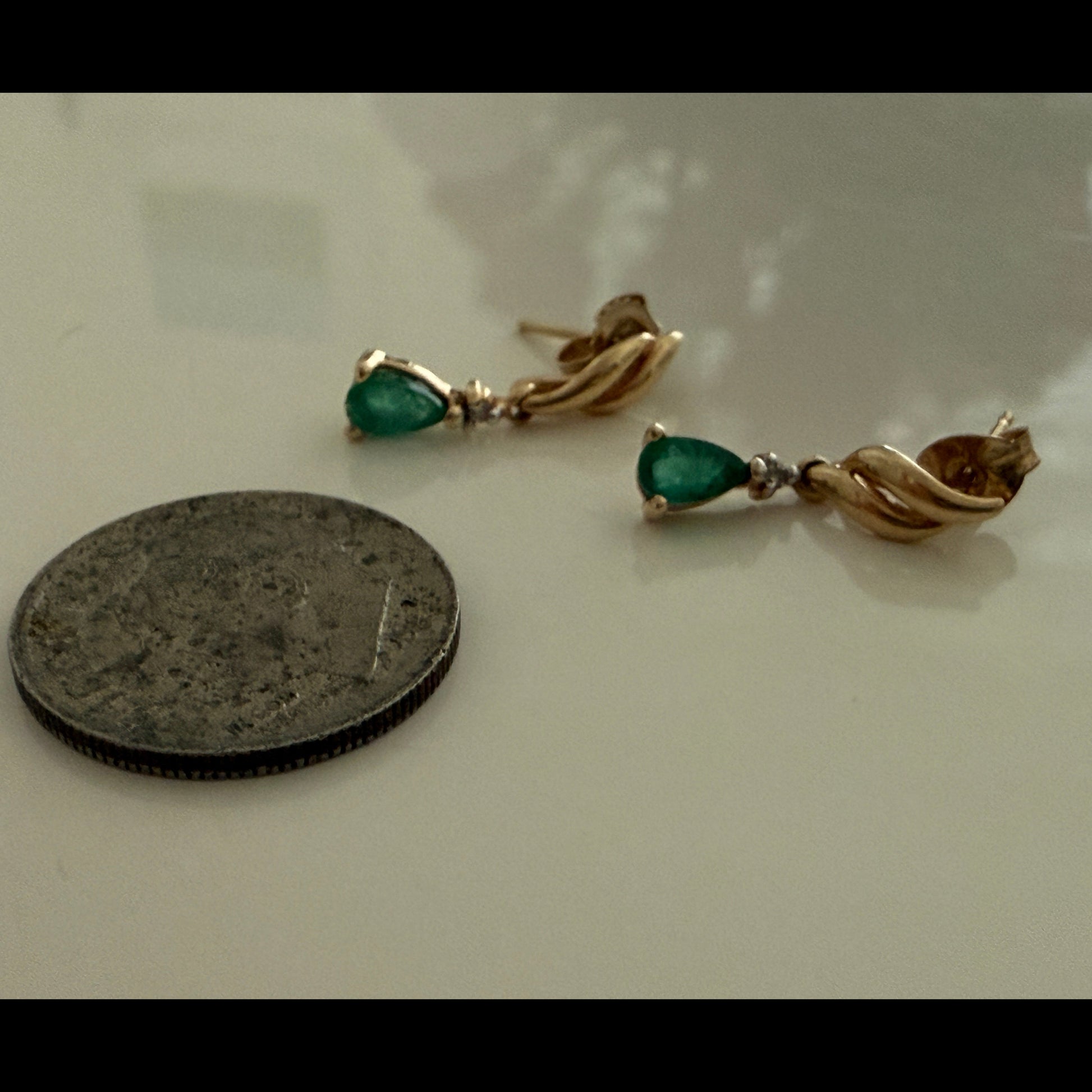 1990s vintage 10K yellow gold emerald and diamond dangle earrings shown next to a U.S. quarter for size reference