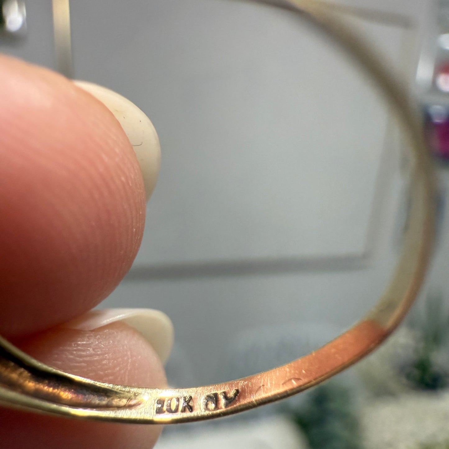 Close-up of 1970s vintage 10K gold ruby and diamond halo ring, showing 10K stamp and partial maker’s mark inside band
