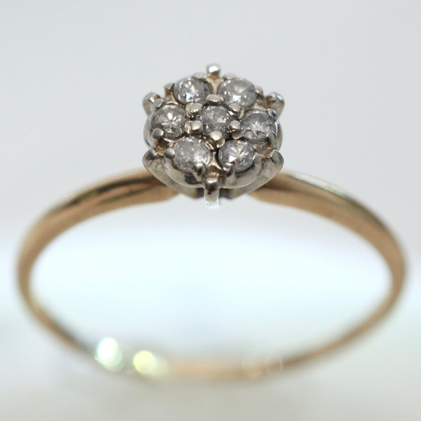 1950s vintage 10K two-tone gold engagement ring with seven round diamond floral cluster, size 7.75, on light background