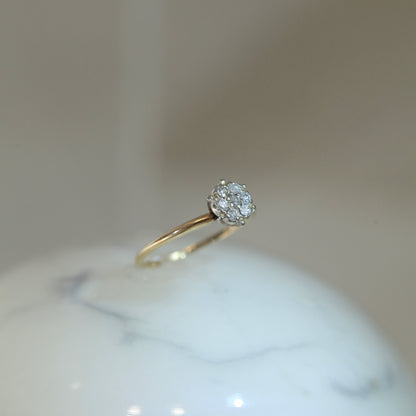 1950s vintage 10K two-tone gold engagement ring with seven-diamond floral cluster, displayed upright on white marble surface with soft neutral background