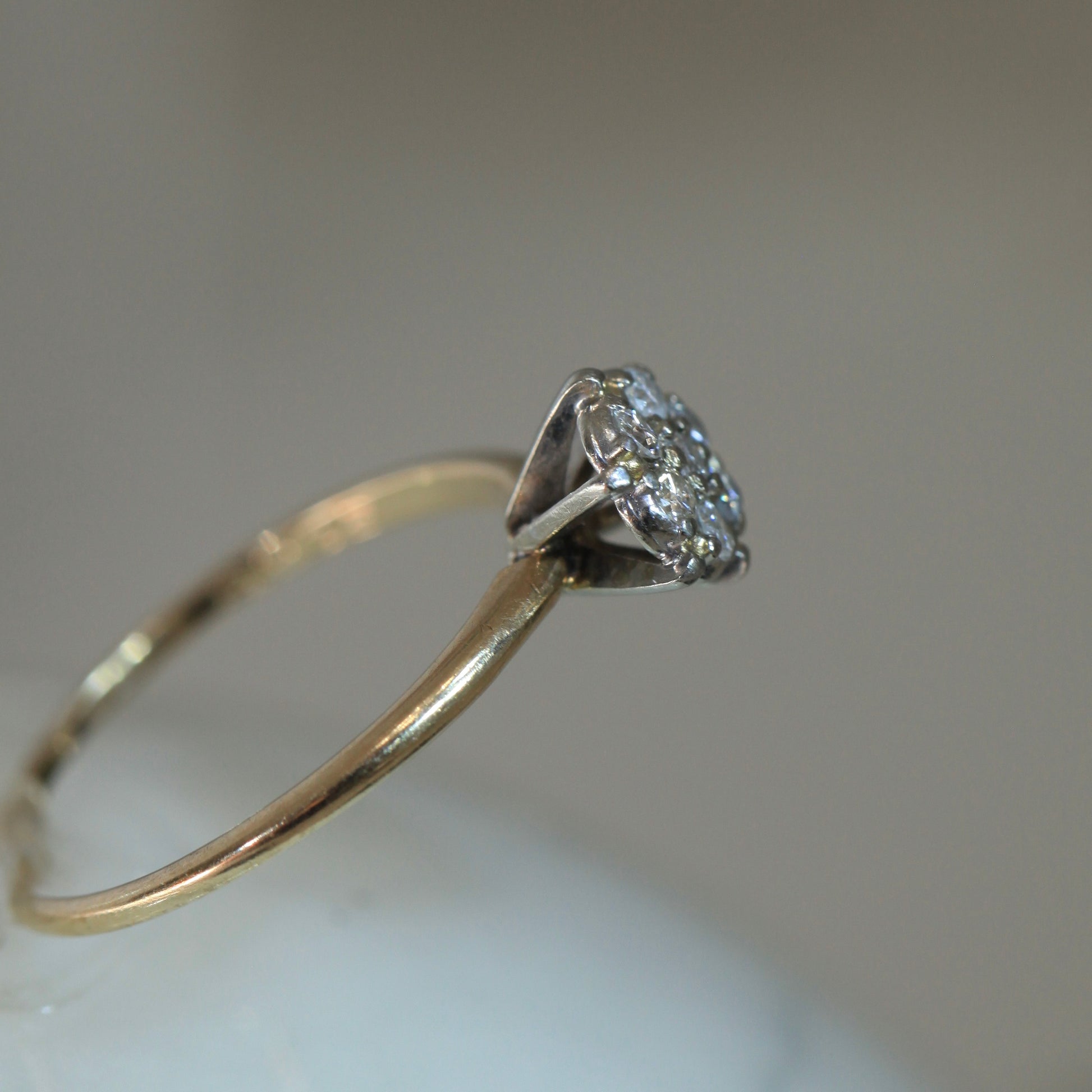 Side profile of 1950s vintage 10K two-tone gold engagement ring with seven-diamond floral cluster, showing illusion head and raised open gallery design