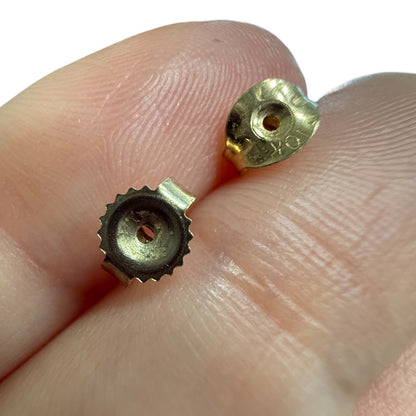 Close-up of vintage 10K yellow gold butterfly earring backs shown against fingers