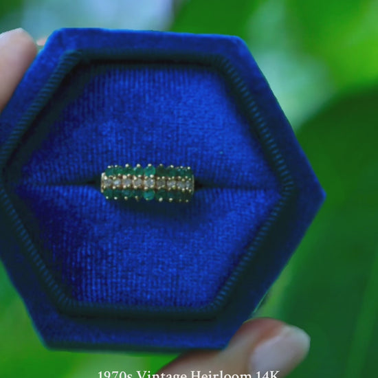 1970s vintage 14K yellow gold emerald and diamond pyramid cocktail ring displayed in a blue velvet jewelry box with green background
