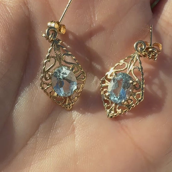 Video of vintage 14K gold filigree aquamarine drop earrings shown on hand in sunlight