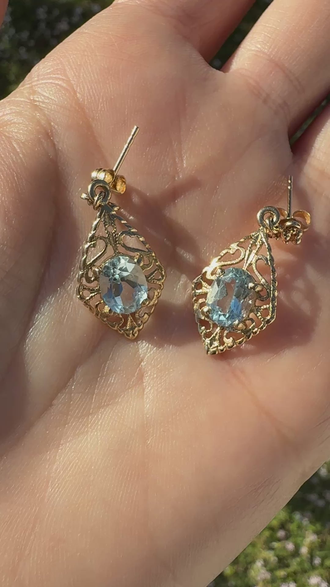Video of vintage 14K gold filigree aquamarine drop earrings shown on hand in sunlight
