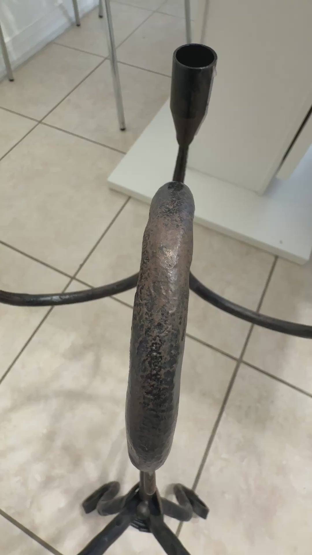 Close-up video of a vintage hand-wrought iron candelabra showing forged surface texture, dark patina, and candle cup detail.