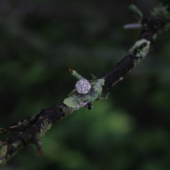 Video of 1950s vintage 10K gold diamond illusion cluster engagement ring with ornate flower motif, rotating under natural light to show sparkle.