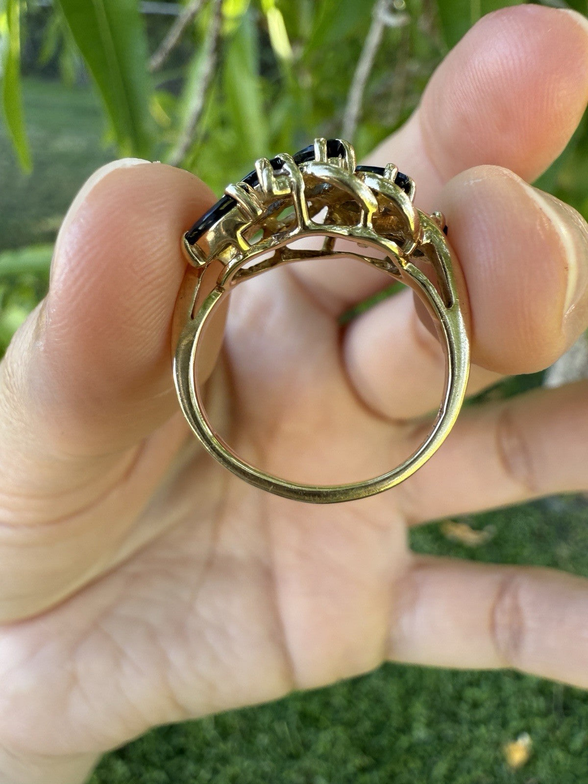 Side profile of vintage 14K gold sapphire and diamond swirl bypass ring showing prong setting and openwork gallery.