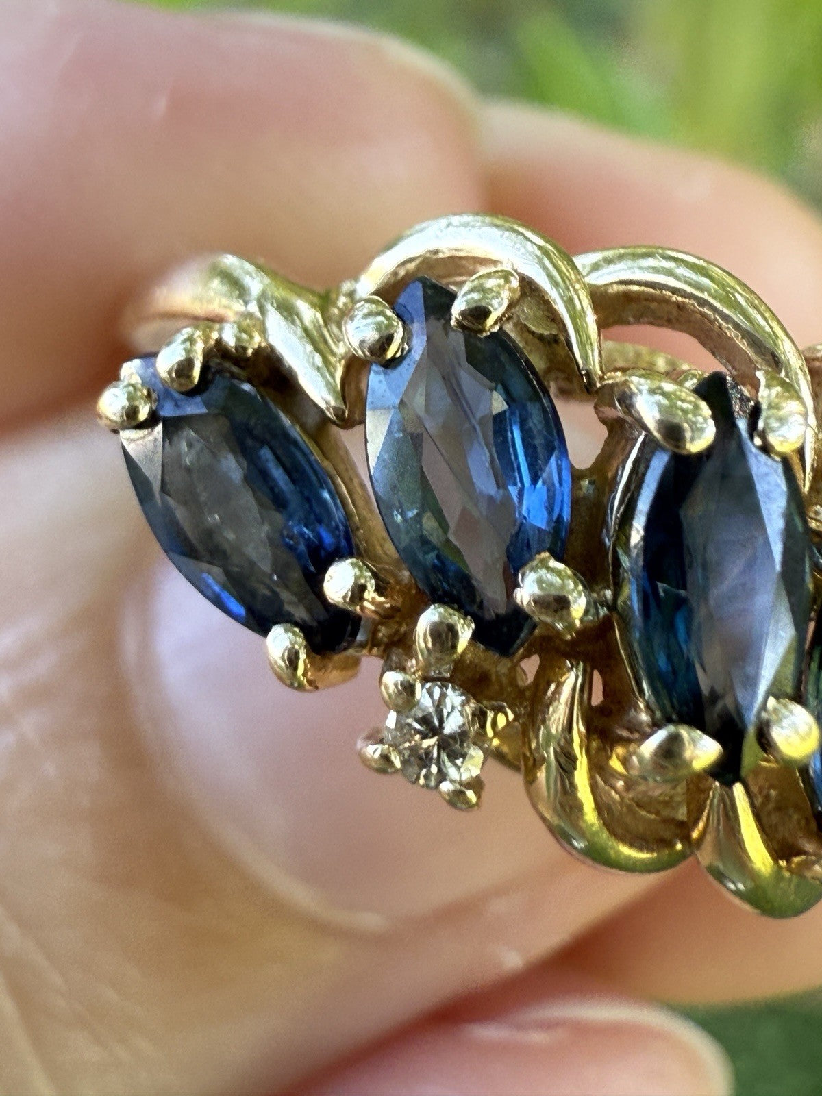 Close-up of vintage 1960s 14K gold sapphire and diamond swirl bypass ring, marquise blue sapphires and accent diamonds in gold setting.