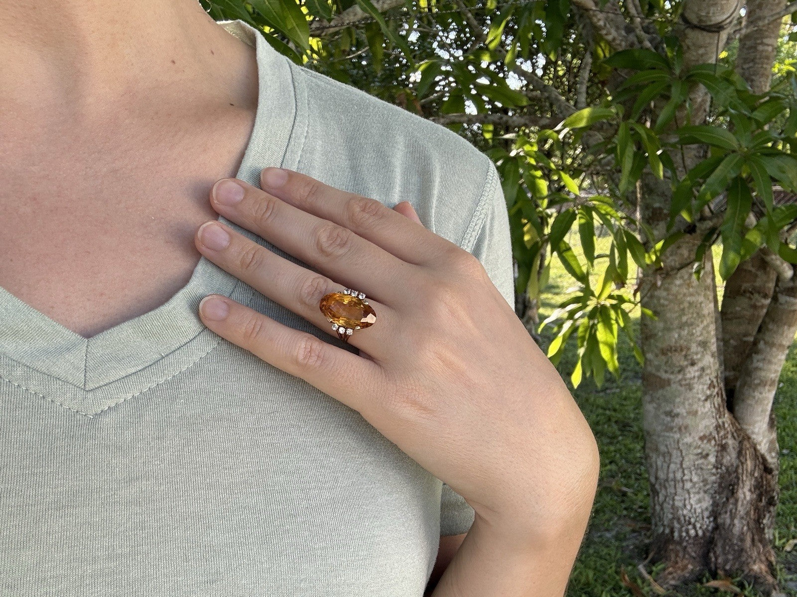 1950s 14K gold citrine and diamond cocktail ring worn on hand resting against chest outdoors
