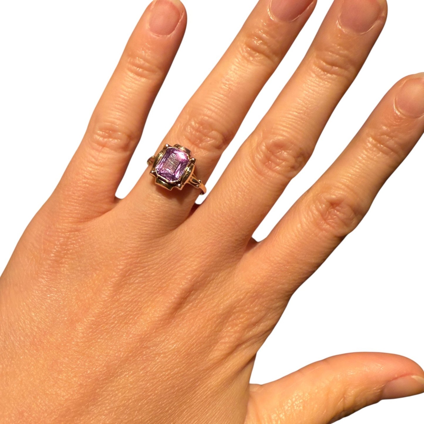 Vintage mid-century 10K yellow gold ring with an emerald-cut lavender amethyst, worn on a hand against a white background.