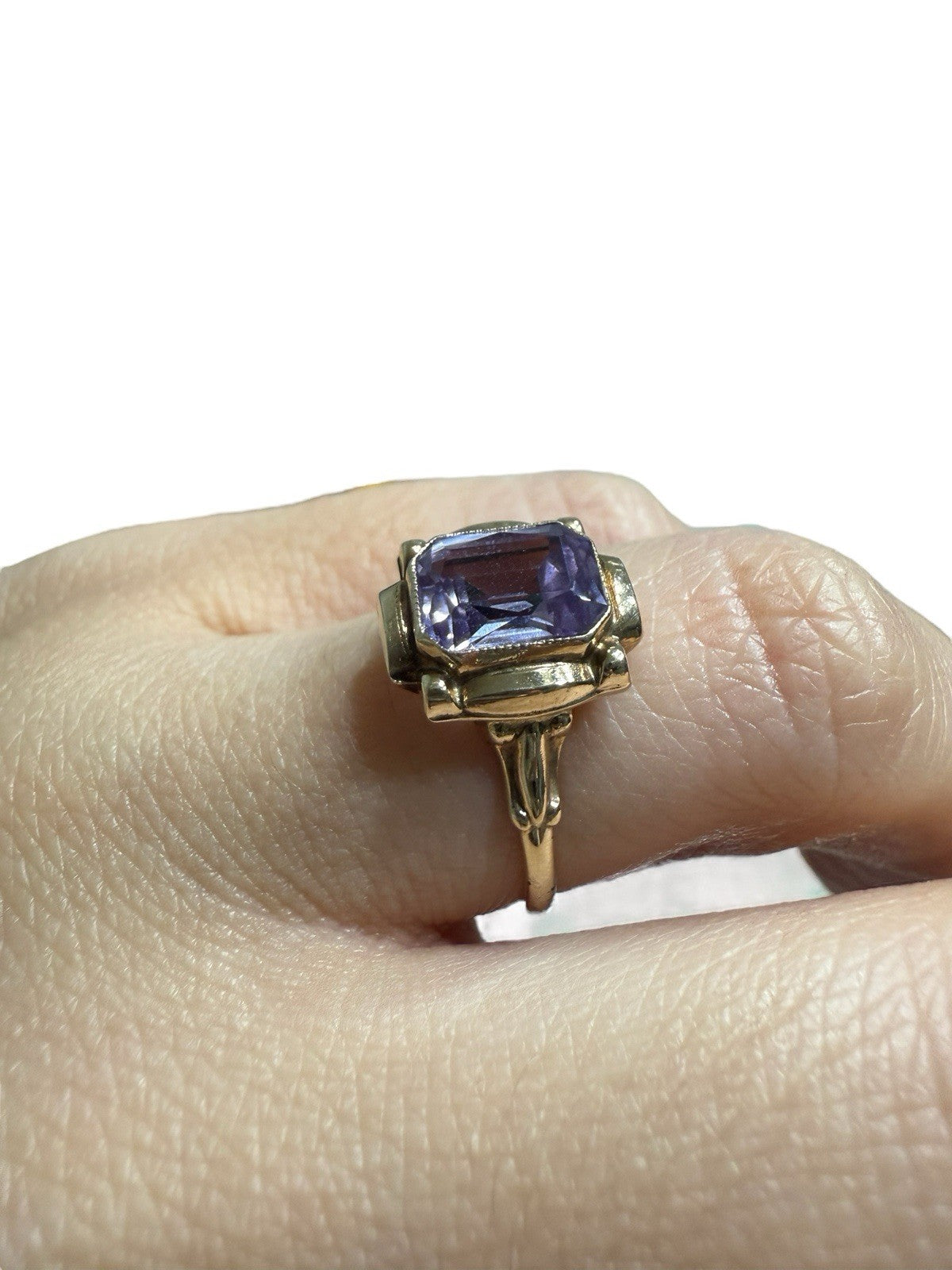 Vintage mid-century 10K yellow gold ring with an emerald-cut lavender amethyst, worn on a finger against a white background.