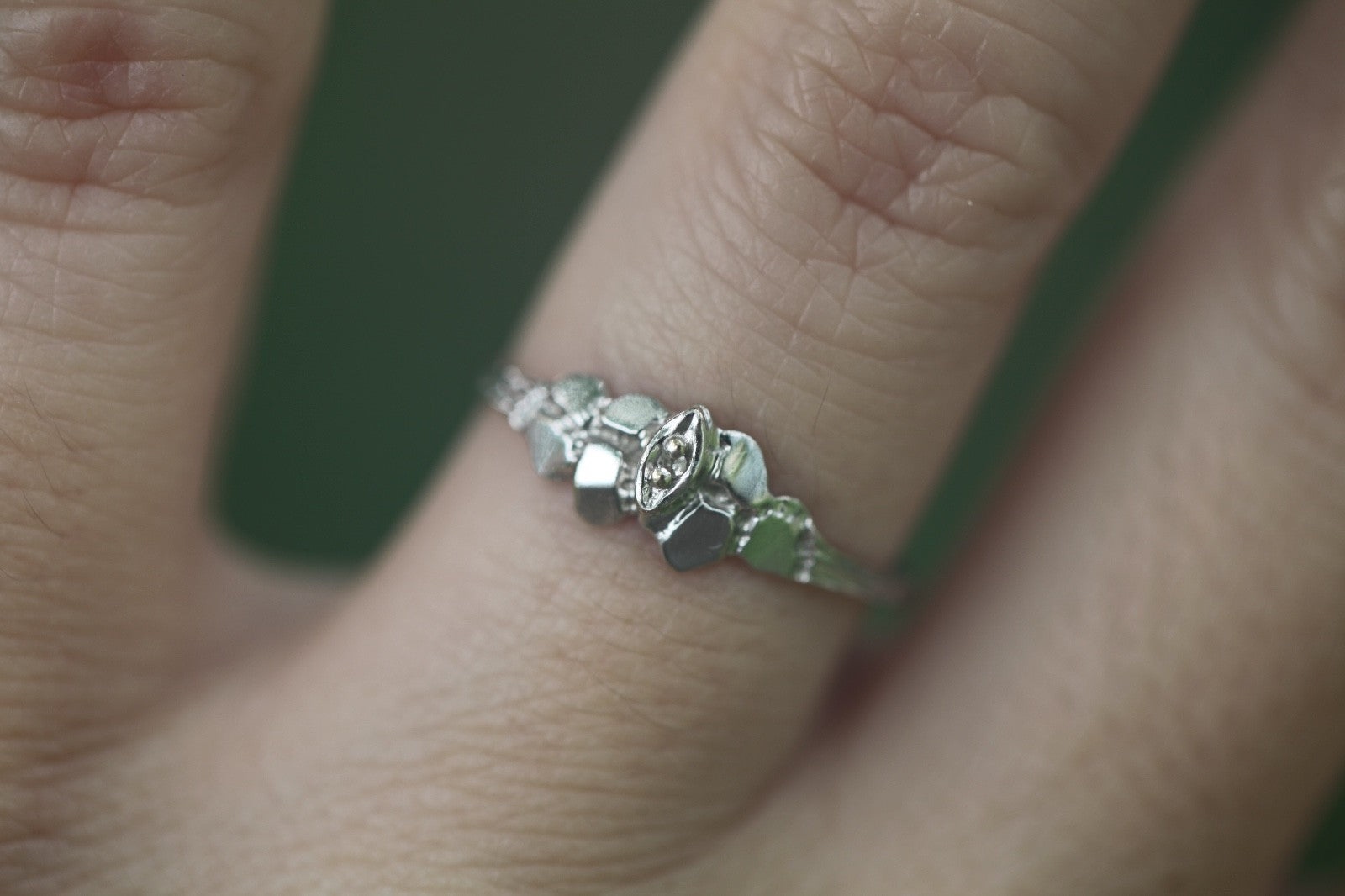 1950s vintage 10K white gold illusion marquise diamond twig band ring on hand against blurred green background