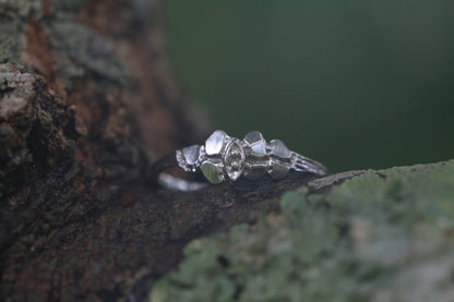 1950s vintage 10K white gold illusion marquise diamond twig band ring displayed on bark with green moss