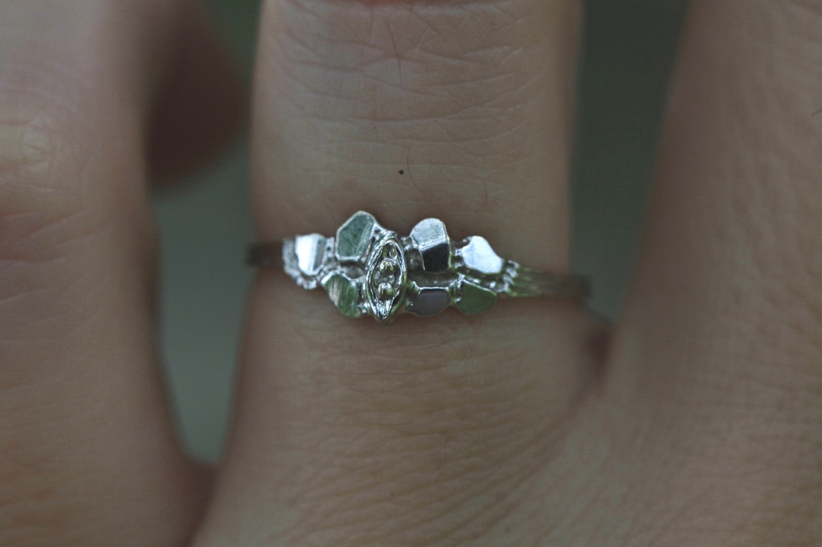 Close-up of 1950s vintage 10K white gold twig band illusion marquise diamond ring on finger, size 5.75