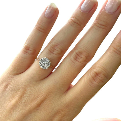 1950s vintage 10K gold diamond illusion cluster ring with flower motif, shown on hand against white background.