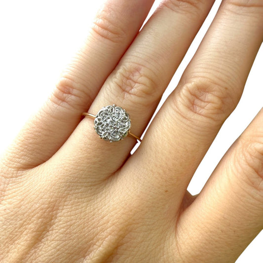 1950s vintage 10K gold diamond illusion cluster ring with flower motif, shown on hand against white background.