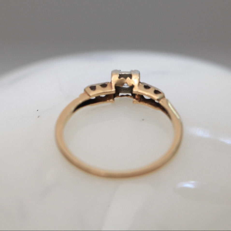 Back view of 1940s vintage 14K two-tone diamond engagement ring, showing under-gallery craftsmanship and band details on white marble surface.