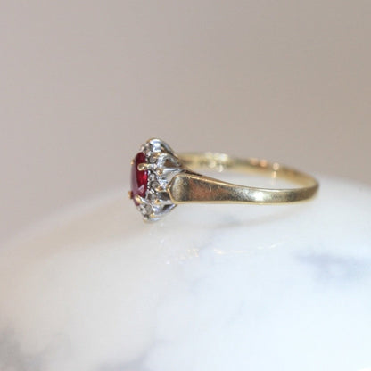 Profile view of 1970s vintage 10K gold ruby and diamond halo ring, marquise cut ruby with diamond cluster, photographed on white marble surface