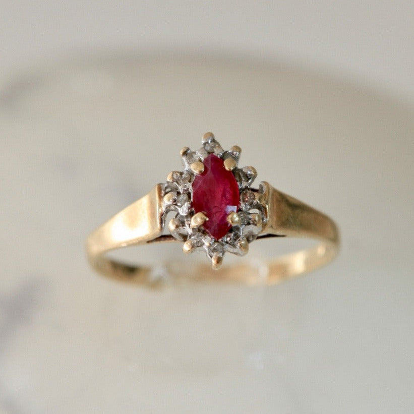 1970s vintage 10K gold ruby and diamond halo ring, marquise cut, size 5.75, photographed on white marble background