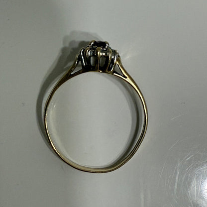 Side profile of 1970s vintage 10K gold ruby and diamond halo ring, marquise cut with raised gallery setting, photographed on gray surface
