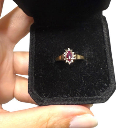 1970s vintage 10K gold marquise ruby and diamond halo cluster ring displayed in a black velvet ring box.