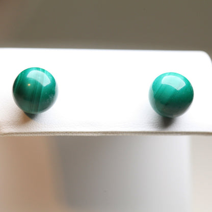 Close-up of vintage 1980s 10mm malachite stud earrings on white display card
