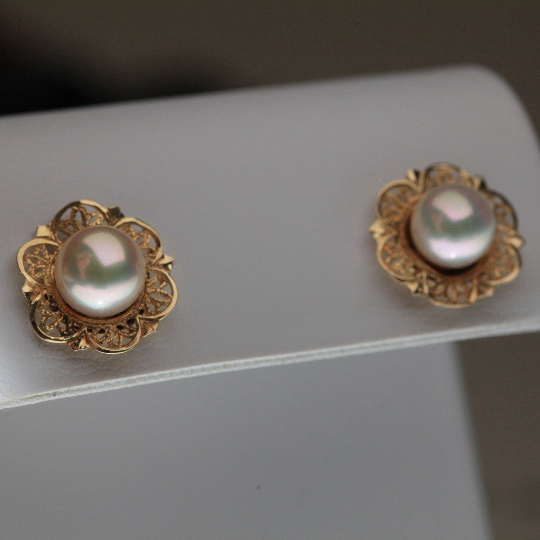 1960s vintage 14K yellow gold filigree flower stud earrings with cultured pearls on a white display stand