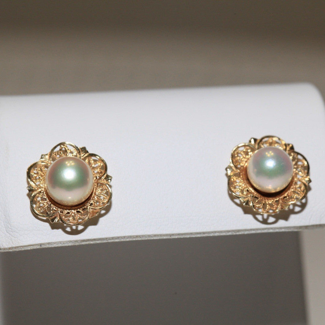 1960s vintage 14K yellow gold filigree flower stud earrings with cultured pearls displayed on a white card against a dark background