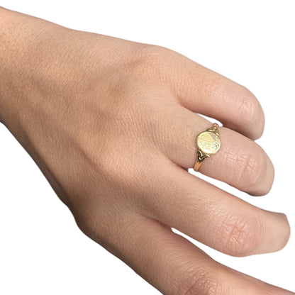 Antique Edwardian 14K gold oval signet ring worn on finger against a white background