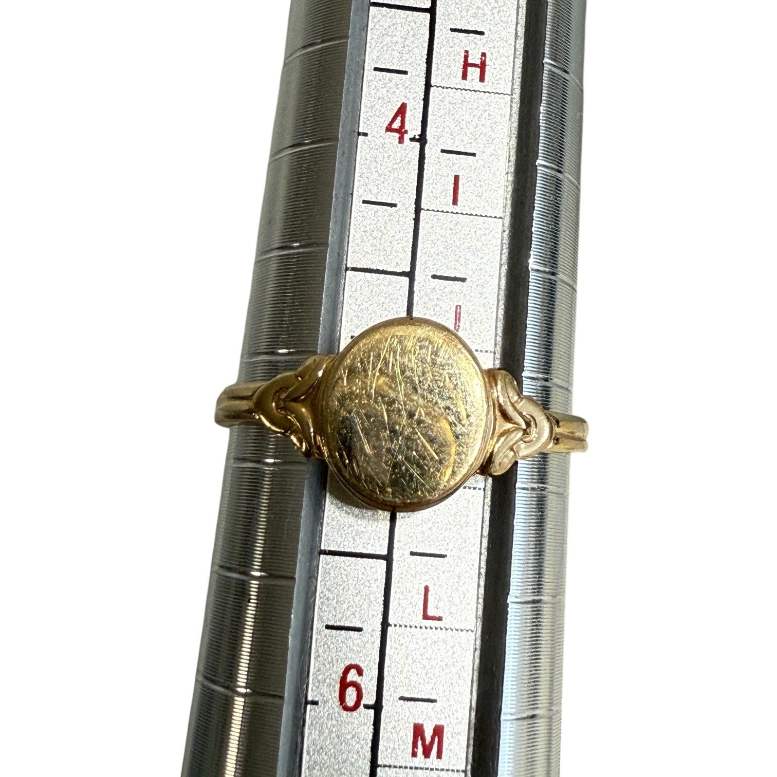 Antique Edwardian 14K gold oval signet ring shown on mandrel confirming size 5, white background