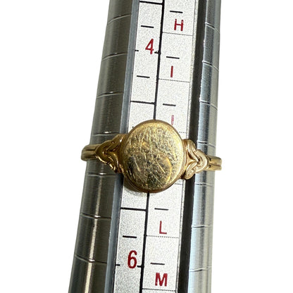 Antique Edwardian 14K gold oval signet ring shown on mandrel confirming size 5, white background