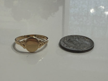 Antique Edwardian 14K gold oval signet ring shown beside a U.S. coin for size reference on white surface
