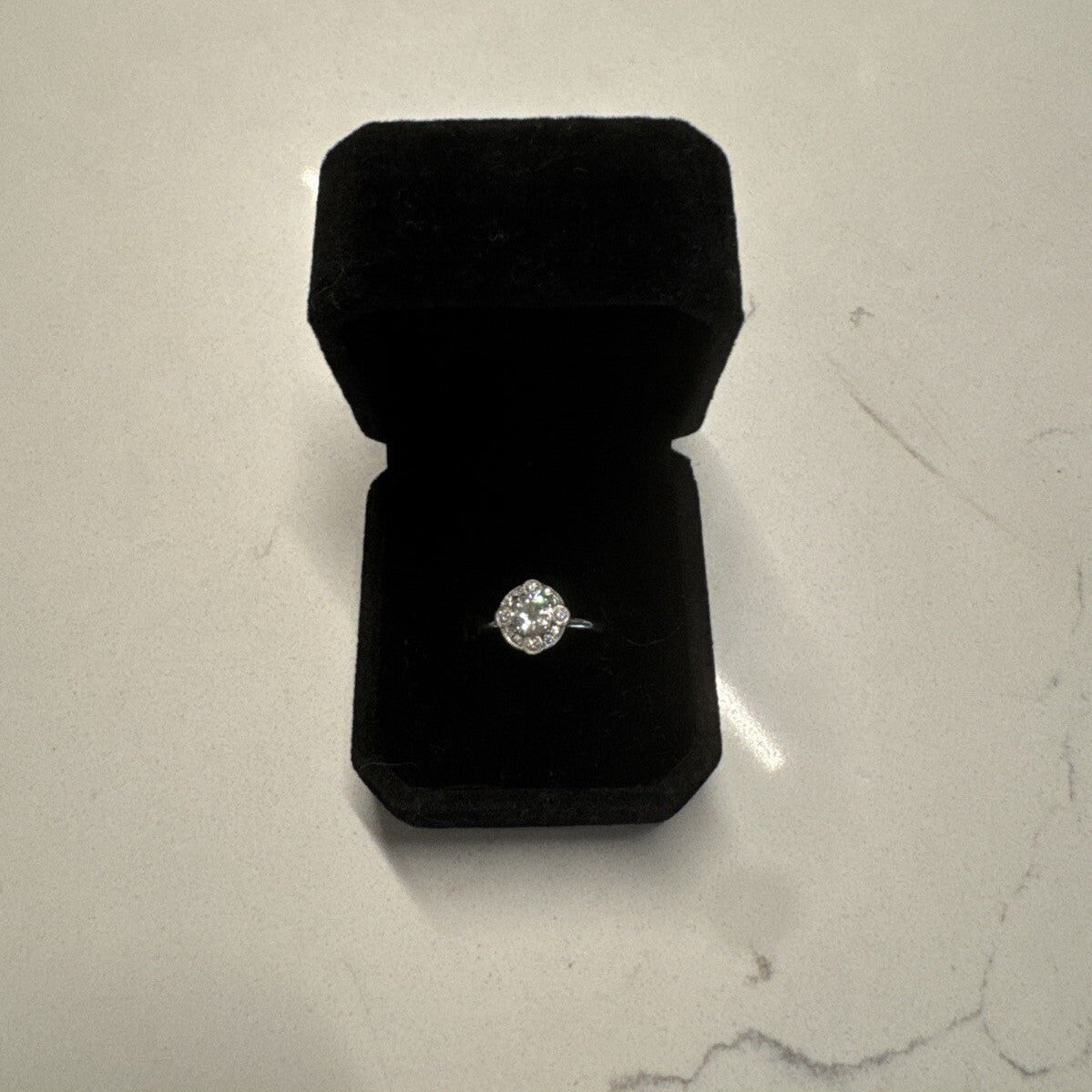 18K white gold diamond ring presented in a black velvet ring box on a light stone surface