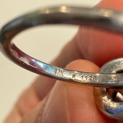 Close-up of an 18K white gold ring band showing engraved maker’s mark and serial number