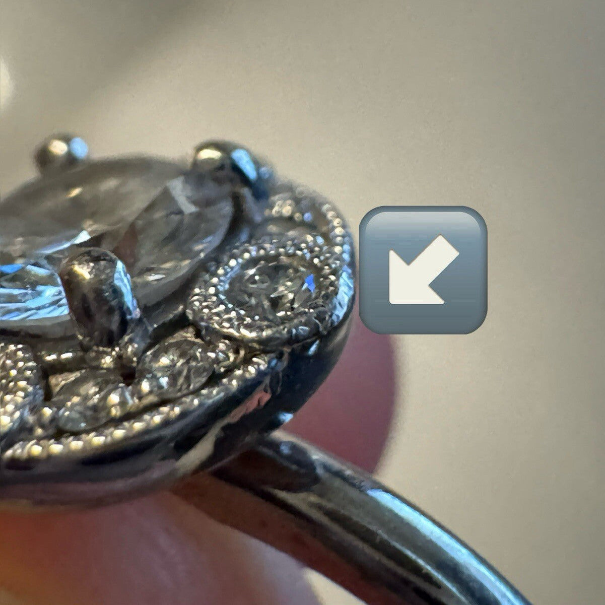 Close-up of an 18K white gold diamond halo ring showing filigree edge and pavé diamond detailing