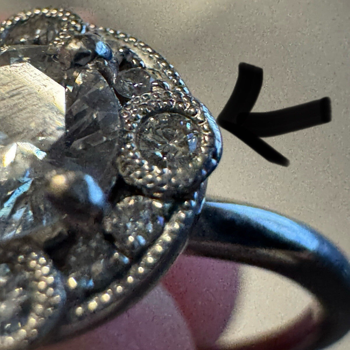 Macro close-up of an 18K white gold diamond halo ring highlighting filigree and pavé detailing