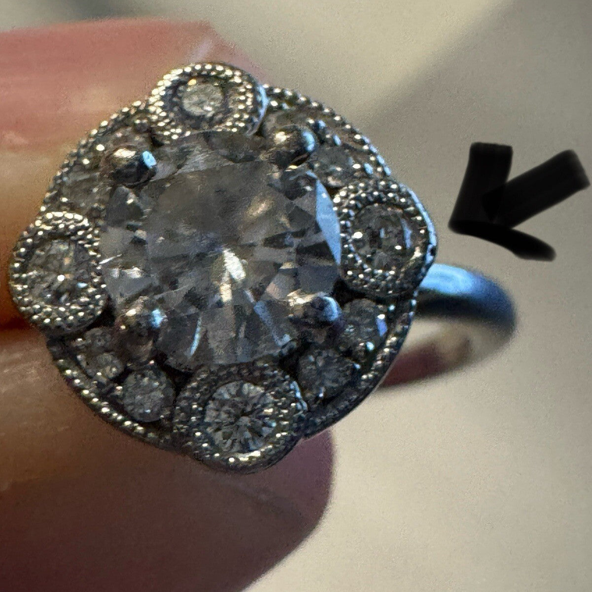 Close-up of an 18K white gold diamond halo ring showing filigree detail and band profile